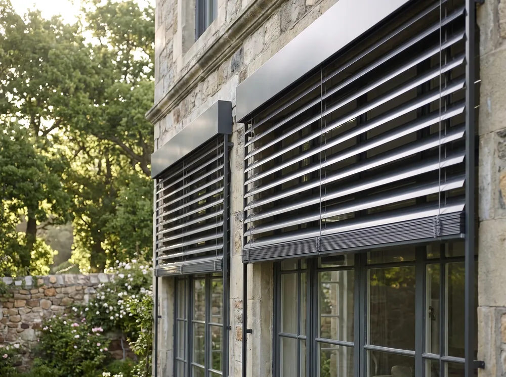 External aluminium venetian blinds mounted outside windows on a Newlands stone facade