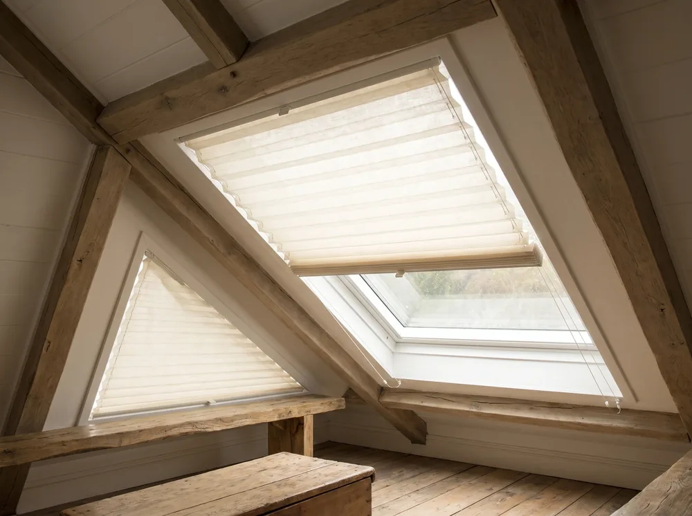 Pleated blinds fitted to an angled skylight and a triangular gable window in a Newlands attic